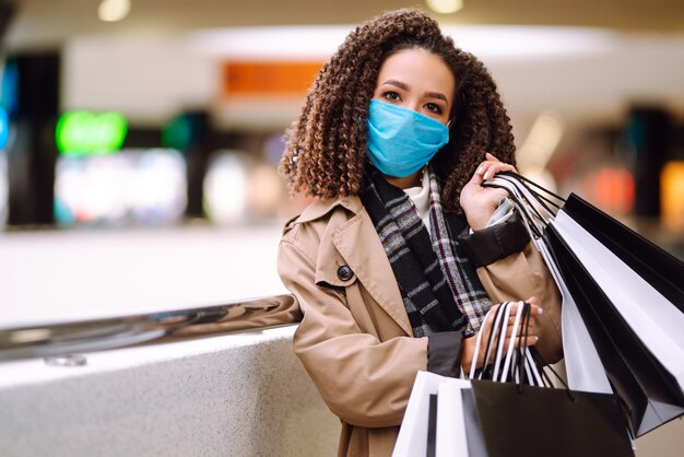 Beautiful african american woman in protective mask after shopping near the store