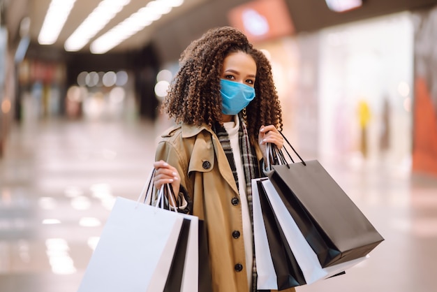 Beautiful african american woman in protective mask after shopping near the store