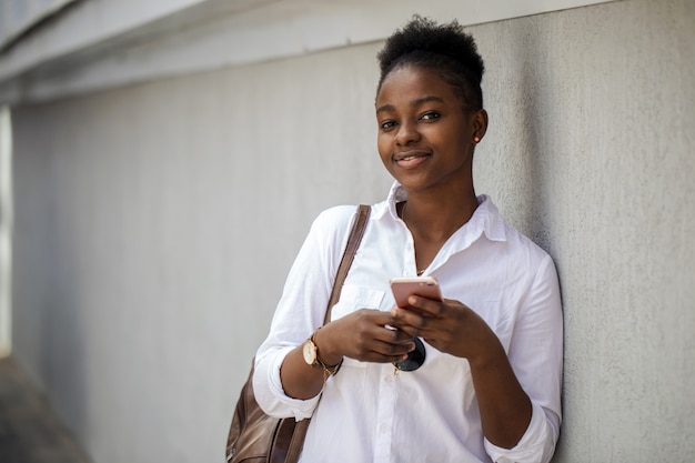 Beautiful african american woman in the street against the white wall