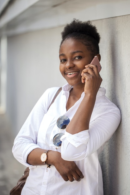 Beautiful african american woman in the street against the white wall