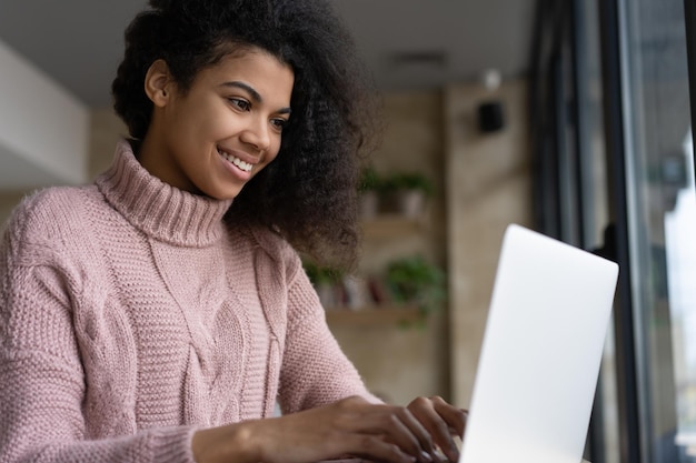 Beautiful African American woman using laptop computer communication online working from home