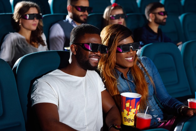 beautiful African couple enjoying a movie at the cinema smiling cheerfully