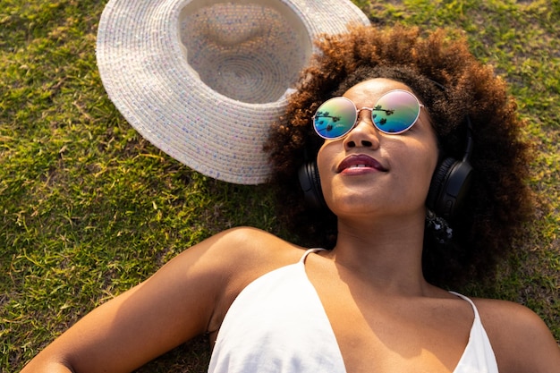 Beautiful african girl happy listening to music on the grass