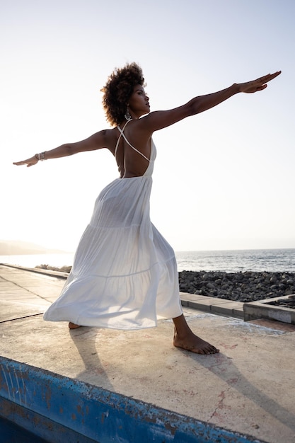 Beautiful african woman in yoga position with sunset background