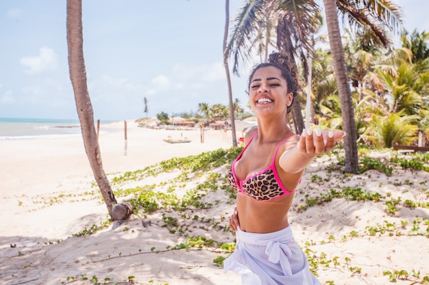 Beautiful afro woman on vacation at the beach. Afro woman extending hand for travel invitation