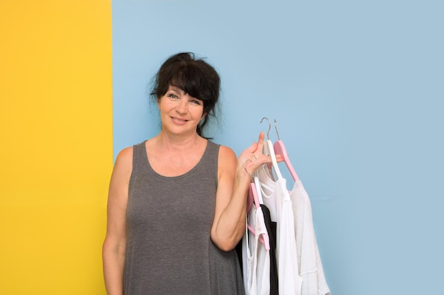 Beautiful age lady smiling holds hangers with women's clothes in her hands second life