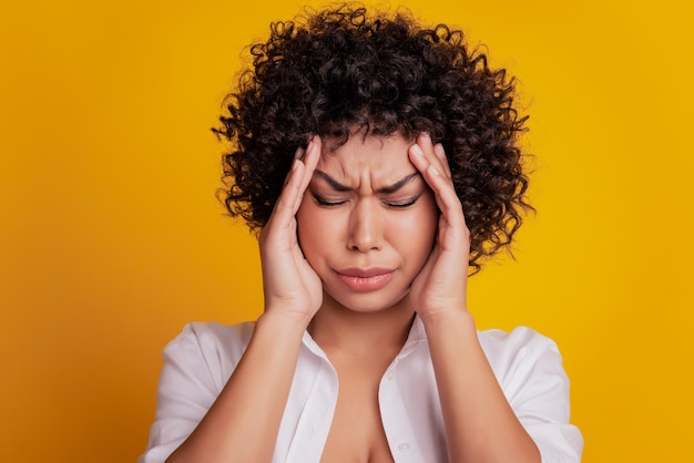 Beautiful annoyed unhealthy lady have headache touch temples close eyes posing on yellow background