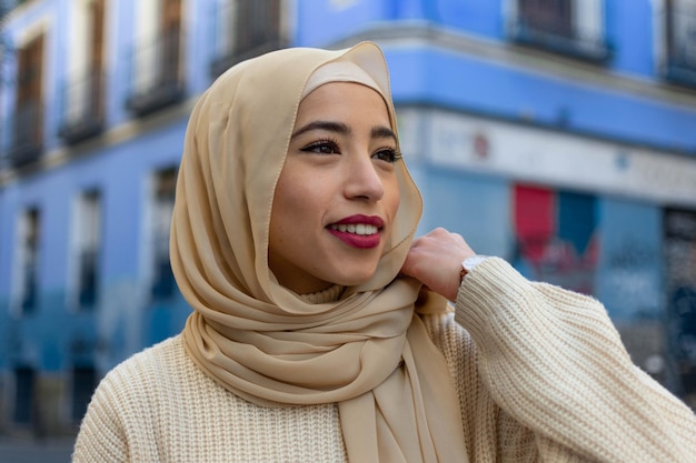 Beautiful arabic girl with hijab outdoors on blue background