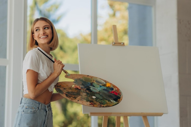 Beautiful artist in her studio Happy girl likes to draw Place for text