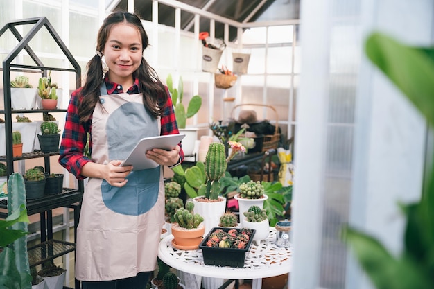 Beautiful Asia owner small business woman use tablet at small shop cactus