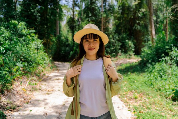 Beautiful Asia woman travelertravel concept woman traveler with backpack holding hat and looking at amazing mountains and forest