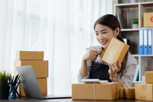 A beautiful Asian business owner opens an online store she is checking orders from customers sending goods through a courier company concept of a woman opening an online business