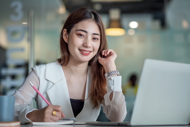 Beautiful asian businesswoman or financial manager working in modern office on laptop