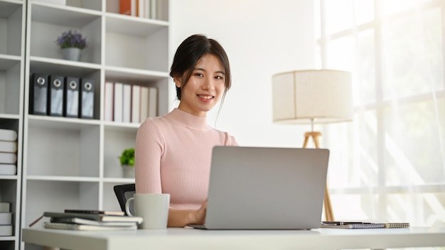 A beautiful Asian businesswoman sitting at her desk in her modern private office