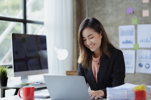 A beautiful Asian businesswoman sitting in her private office she is checking company financial documents she is a female executive of a startup company Concept of financial management