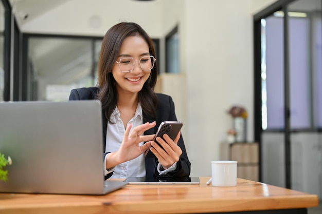 Beautiful Asian businesswoman using her smartphone at her desk