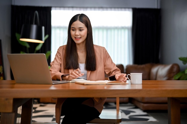 Beautiful Asian businesswoman using laptop computer working in her private office