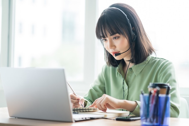 Beautiful asian customer service lady is calling customers to offer products