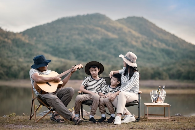 Beautiful Asian family doing picnic and in Easter summer party on a meadow near lake and mountain. Holiday and Vacation. People's lifestyle and Happy family life concept.