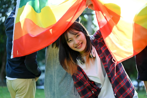 Beautiful Asian female college student holding LGBT rainbow flag with her friends Unity of minority