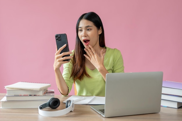 A beautiful Asian female college student is looking at her smartphone screen with a surprising face