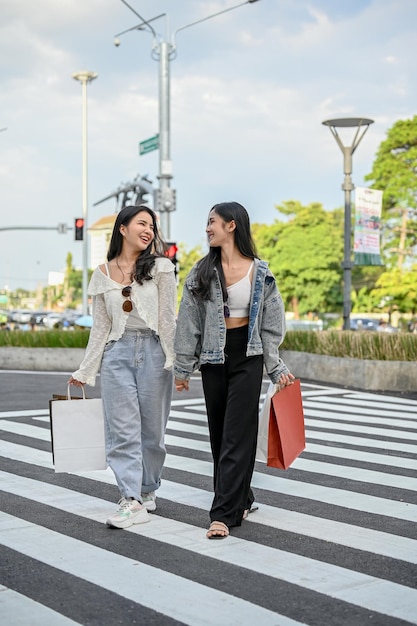 Beautiful Asian female crossing the crosswalk with her friend walking down the shopping street