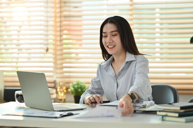 Beautiful asian female financial advisor using laptop chatting with client online or giving internet consultation to customer