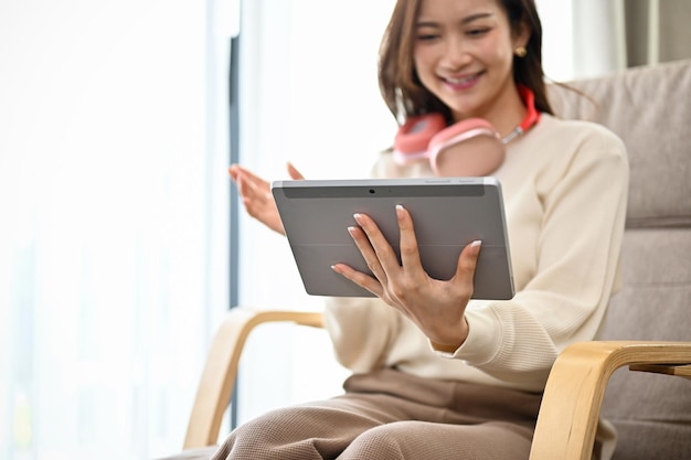 Beautiful Asian female relaxes in the living room using a digital tablet touchpad