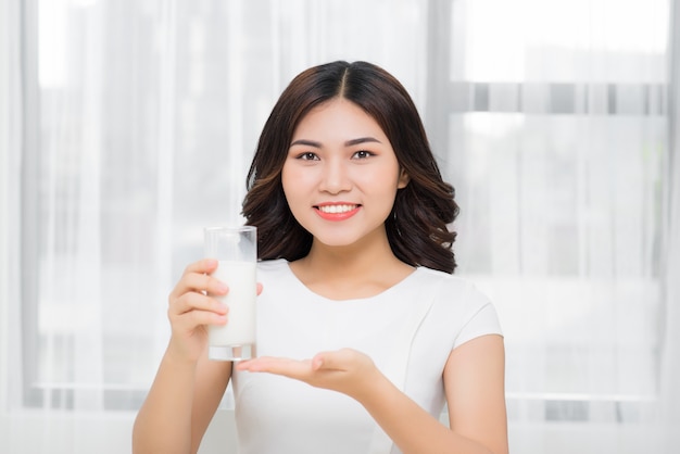 Beautiful asian girl drinking a glass of milk.