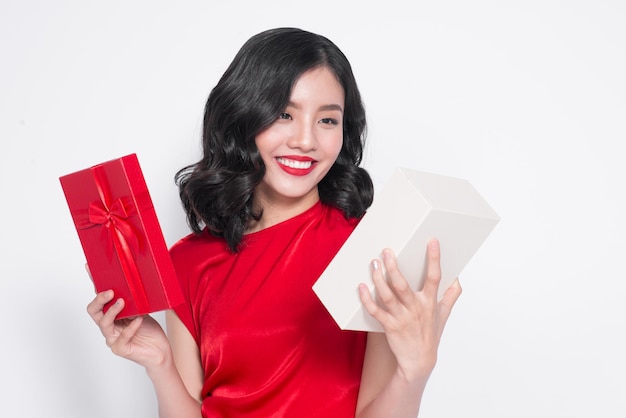 Beautiful Asian girl holding a present in her hands and smiling against the white background