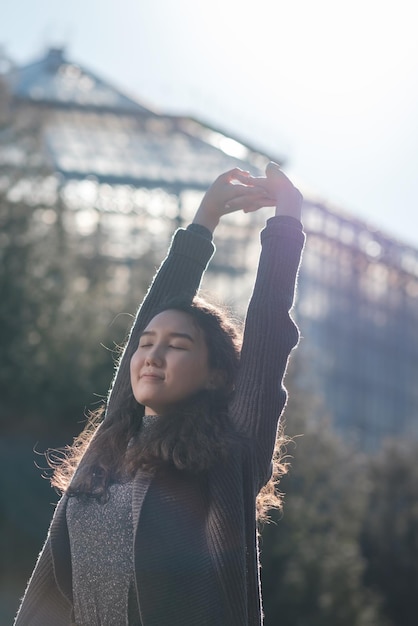 A beautiful Asian girl is standing in the park and resting basking in the sun Enjoy the silence in city life