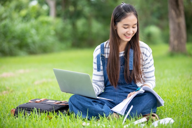 Beautiful Asian girl student holding books and smiling  and learning and education   on park in summer for relax time