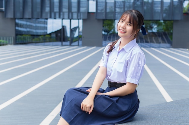 Beautiful Asian high school student girl in school uniform with smiles confidently while she happily