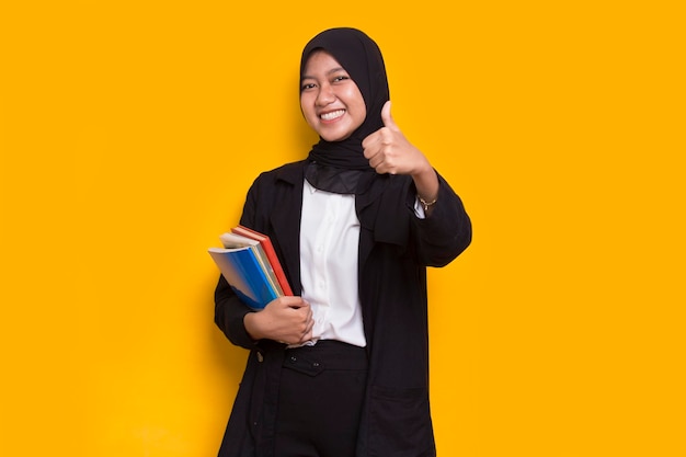 beautiful asian muslim business woman hug a book isolated on yellow background