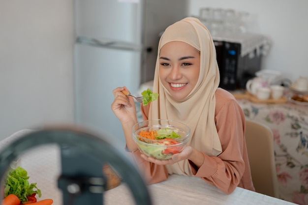 A beautiful Asian Muslim female food blogger is recording her cooking show and eating video