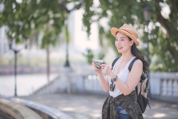 Beautiful asian solo tourist woman enjoy taking photo by retro camera at tourist sightseeing spot. 