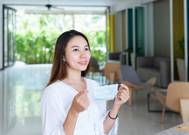 Beautiful Asian traveler woman holding protective face mask on her hands New normal health care travel and holiday concept