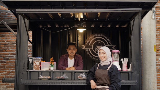 Photo beautiful asian waitress and cool handsome guy at the angkringan container booth