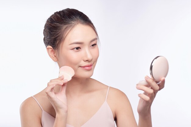 Beautiful asian woman applying powder puff at cheek makeup of cosmetic, beauty of girl with face smile