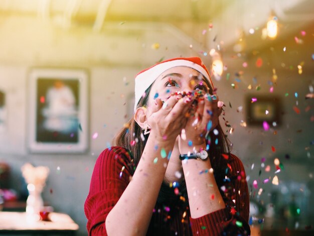 Beautiful Asian woman blows glitter confetti. Christmas party concept.