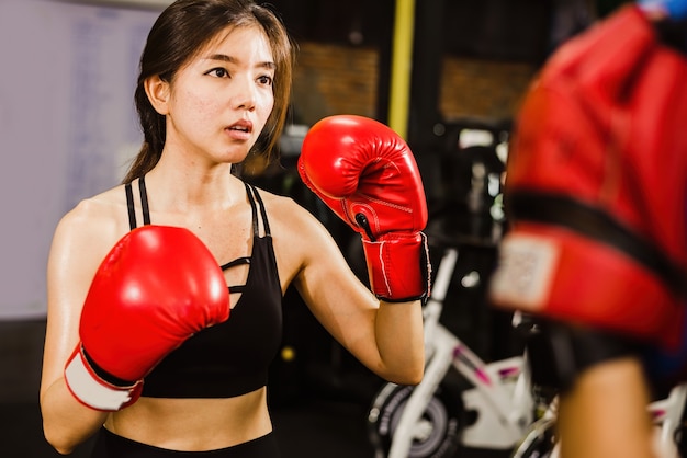 Beautiful Asian woman boxer practicing boxing in a fitness gym.