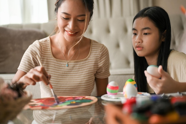 Beautiful Asian woman enjoy painting Easter egg with her younger sister in their house