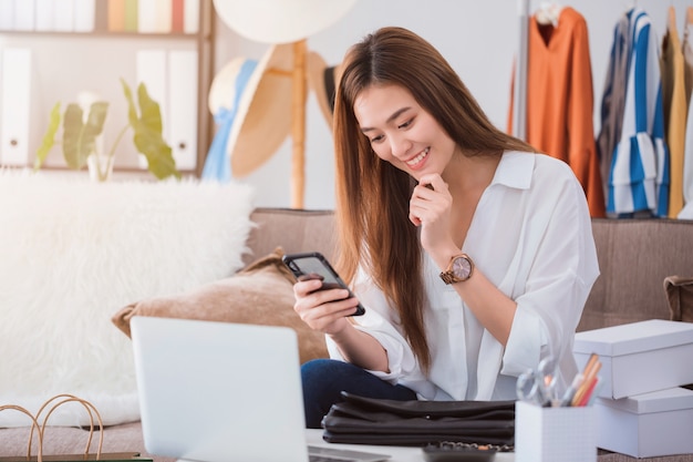 Beautiful asian woman fashion designer blogger sitting in the clothing store.