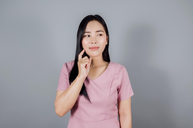 Beautiful asian woman on gray background holding hand near the face