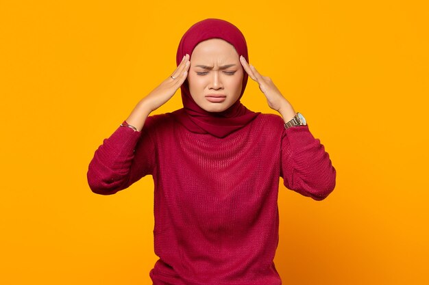 Photo beautiful asian woman holding her temples having a headache wi