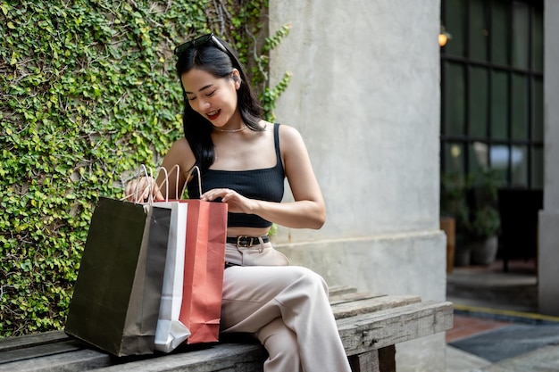 A beautiful Asian woman is checking her purchased stuff in shopping bags enjoying her shopping day