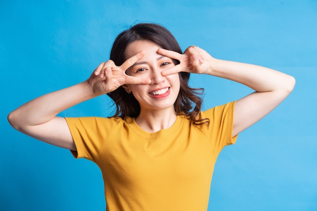 The beautiful Asian woman is forming a peace symbol with her hand