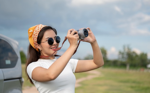 A beautiful Asian woman is taking pictures with her camera during her countryside summer vacation