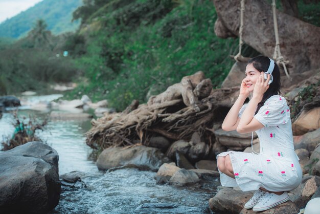 Beautiful Asian woman listening to music at the river