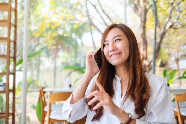 A beautiful asian woman talking on mobile phone with smiling face in cafe